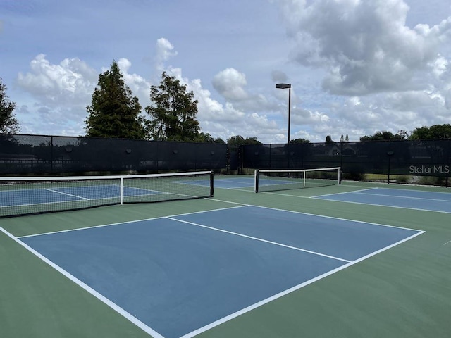 view of tennis court featuring community basketball court and fence