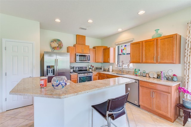 kitchen with appliances with stainless steel finishes, a sink, light tile patterned flooring, recessed lighting, and a kitchen island