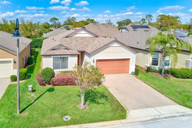 view of front of house featuring stucco siding, an attached garage, decorative driveway, and a front yard