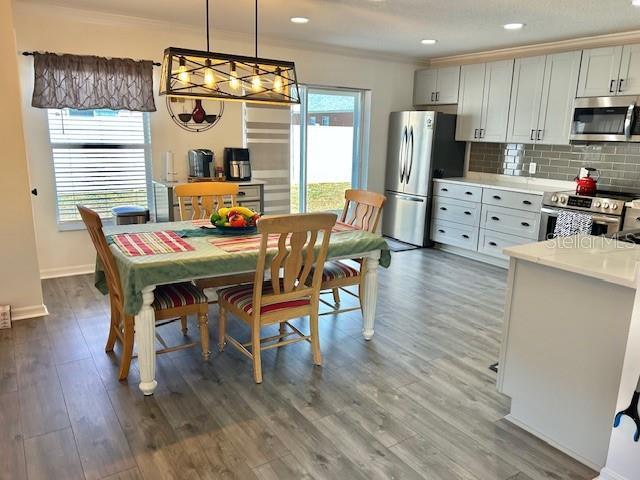 dining room with ornamental molding, dark wood-type flooring, baseboards, and recessed lighting