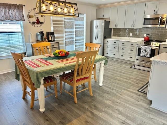 dining room with light wood-style flooring, baseboards, a chandelier, and ornamental molding