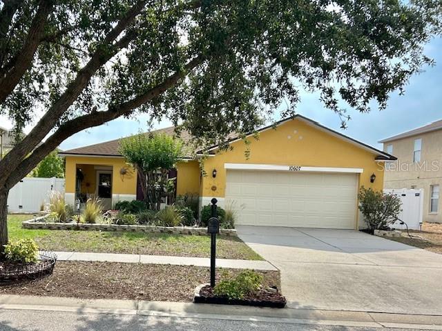 view of front of home with stucco siding, driveway, a garage, and fence