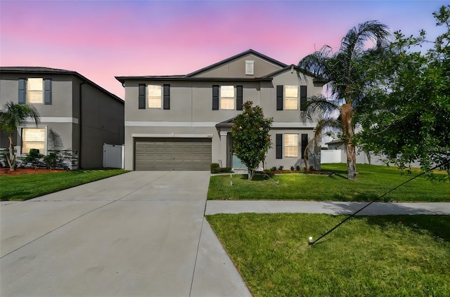 view of front facade with concrete driveway, stucco siding, a garage, and a front lawn