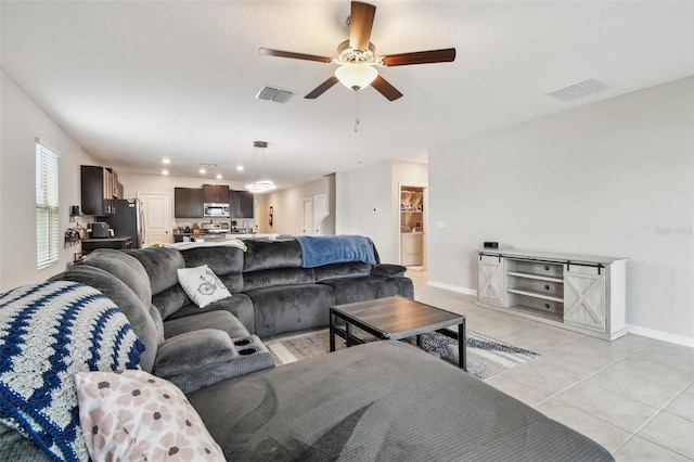 living area with light tile patterned floors, visible vents, baseboards, and a ceiling fan