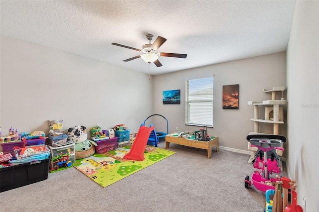 playroom featuring carpet, a textured ceiling, baseboards, and a ceiling fan