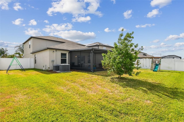 back of house with a fenced backyard, a sunroom, a playground, and a yard