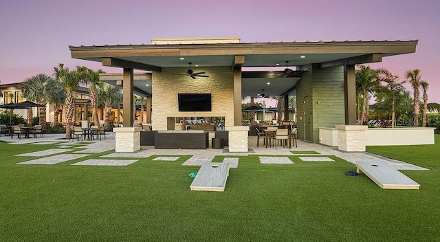 rear view of property with outdoor lounge area, a lawn, exterior bar, ceiling fan, and a patio area