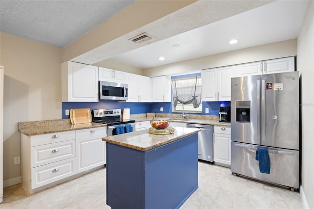 916 Shangri La Dr, Seffner, FL 33584 - kitchen featuring appliances with stainless steel finishes, white cabinetry, light stone counters, and recessed lighting