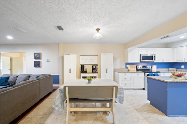 916 Shangri La Dr, Seffner, FL 33584 - kitchen featuring stainless steel appliances, white cabinetry, a textured ceiling, open floor plan, and recessed lighting