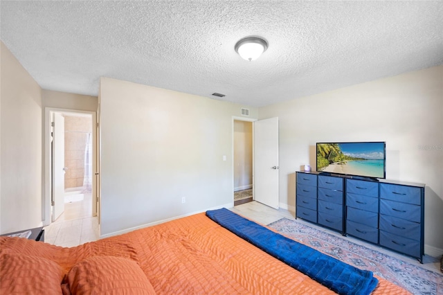 916 Shangri La Dr, Seffner, FL 33584 - bedroom with a textured ceiling, baseboards, ensuite bath, and light tile patterned flooring