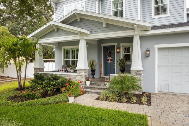 3611 W Royal Palm Cir, Tampa, FL 33629 - view of exterior entry with covered porch, a garage, stone siding, and stucco siding