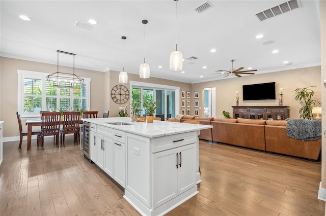 3611 W Royal Palm Cir, Tampa, FL 33629 - kitchen with a sink, crown molding, white cabinetry, light wood-style flooring, and a ceiling fan