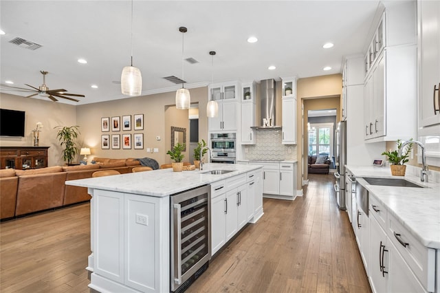 3611 W Royal Palm Cir, Tampa, FL 33629 - kitchen with beverage cooler, wall chimney range hood, white cabinets, recessed lighting, and a kitchen island with sink