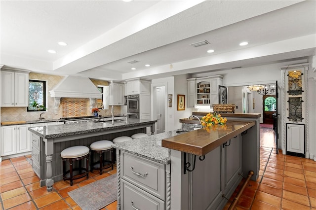 136 W Davis Blvd, Tampa, FL 33606 - kitchen with a spacious island, a kitchen breakfast bar, premium range hood, a sink, and tasteful backsplash