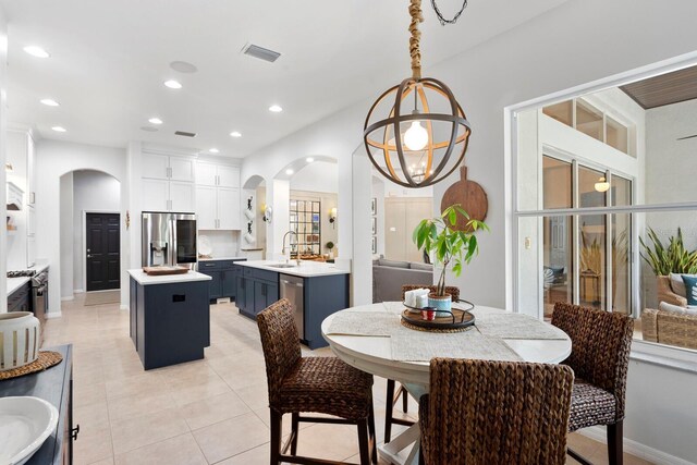 dining room featuring arched walkways, recessed lighting, light tile patterned flooring, a chandelier, and baseboards