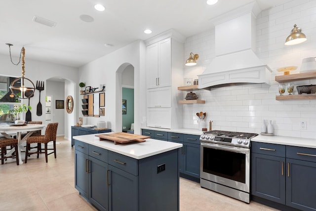 kitchen with stainless steel gas stove, arched walkways, open shelves, blue cabinets, and recessed lighting