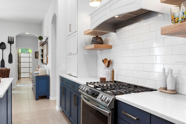 kitchen with blue cabinets, gas stove, arched walkways, and tasteful backsplash