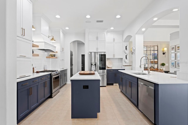 kitchen featuring an island with sink, stainless steel appliances, a sink, tasteful backsplash, and recessed lighting