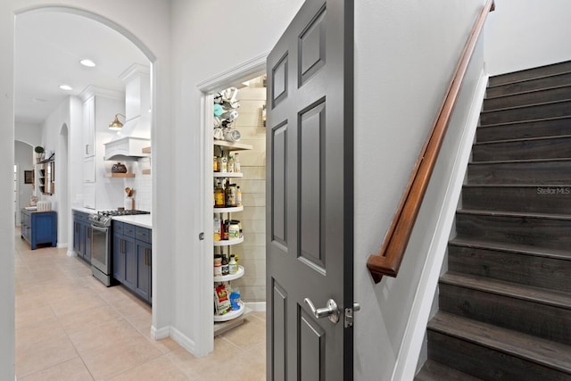 bar area featuring stainless steel gas range, arched walkways, light tile patterned floors, stairway, and recessed lighting