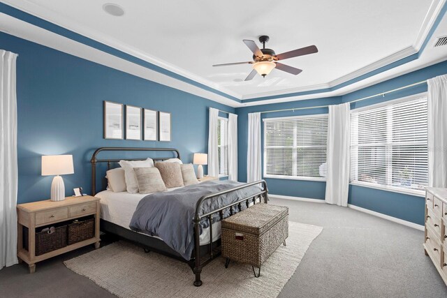 carpeted bedroom featuring a tray ceiling, baseboards, a ceiling fan, and crown molding