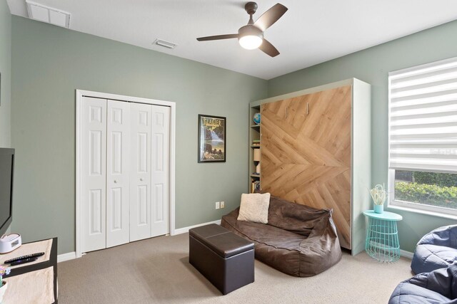 living area with carpet, ceiling fan, and baseboards