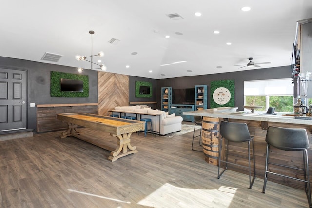 recreation room featuring vaulted ceiling, wooden walls, ceiling fan, wood finished floors, and recessed lighting
