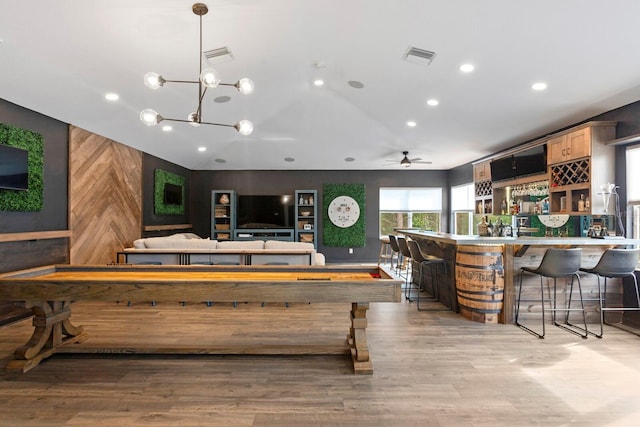game room featuring wood walls, recessed lighting, lofted ceiling, light wood-style flooring, and a community bar