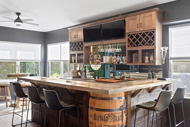 indoor wet bar with a ceiling fan and wood finished floors