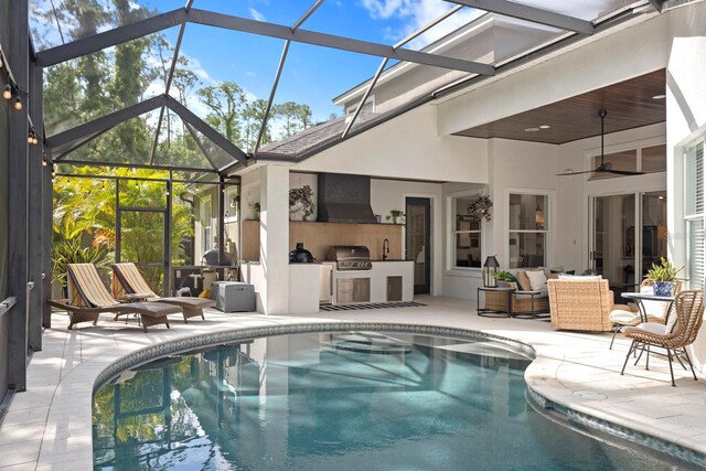 swimming pool with an outdoor kitchen, a patio area, outdoor lounge area, and glass enclosure