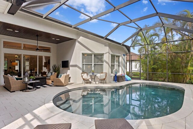 swimming pool featuring outdoor lounge area, a patio area, a ceiling fan, and a lanai