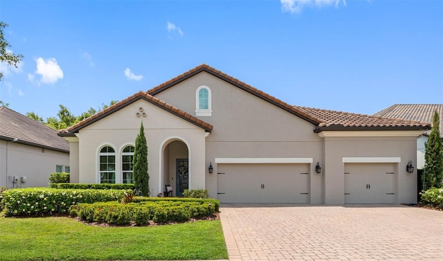 1104 Isobel Reserve Ln, Tampa, FL 33613 - mediterranean / spanish house with a garage, decorative driveway, a tile roof, stucco siding, and a front yard