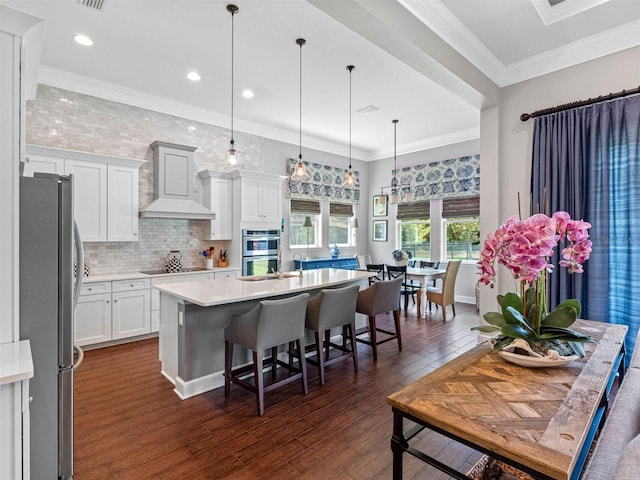 1104 Isobel Reserve Ln, Tampa, FL 33613 - kitchen with appliances with stainless steel finishes, custom exhaust hood, light countertops, an island with sink, and white cabinetry