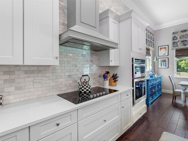 1104 Isobel Reserve Ln, Tampa, FL 33613 - kitchen featuring black electric cooktop, wall chimney exhaust hood, white cabinetry, light countertops, and crown molding