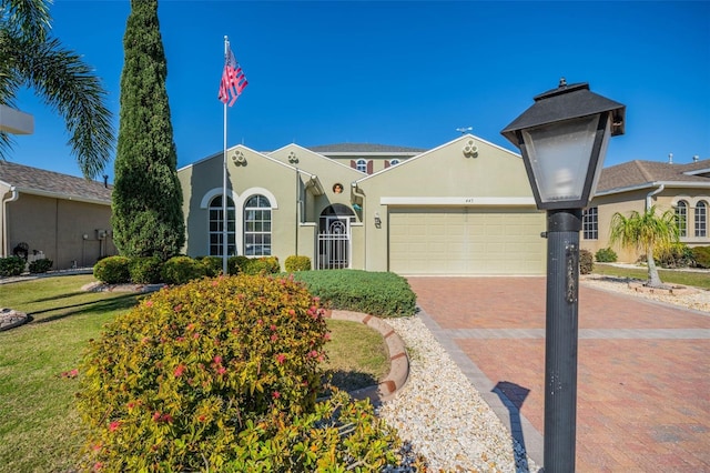 445 Noble Faire Dr, Sun City Center, FL 33573 - view of front of home with an attached garage, decorative driveway, stucco siding, and a front lawn