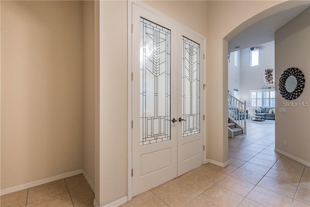 445 Noble Faire Dr, Sun City Center, FL 33573 - foyer featuring arched walkways, french doors, baseboards, light tile patterned flooring, and stairs
