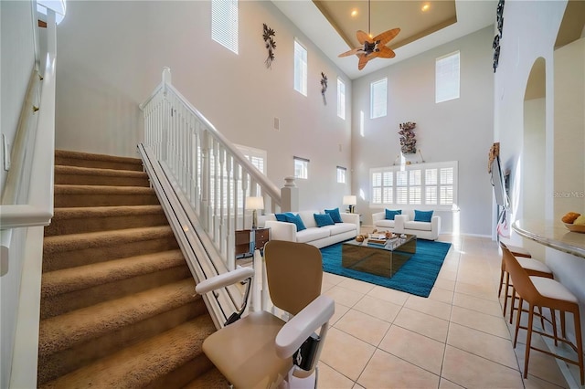 445 Noble Faire Dr, Sun City Center, FL 33573 - living room featuring a ceiling fan, a towering ceiling, light tile patterned flooring, stairs, and baseboards