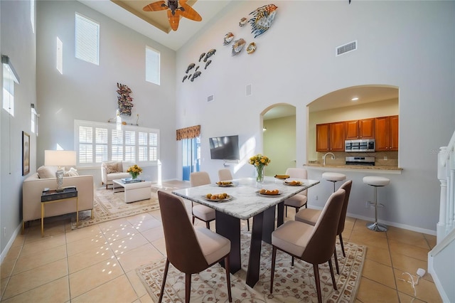 445 Noble Faire Dr, Sun City Center, FL 33573 - dining space featuring arched walkways, a towering ceiling, ceiling fan, light tile patterned floors, and plenty of natural light