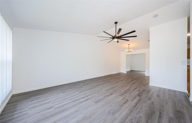 7763 Jenner Ave, New Port Richey, FL 34655 - unfurnished living room featuring a chandelier, vaulted ceiling, wood finished floors, ceiling fan, and baseboards