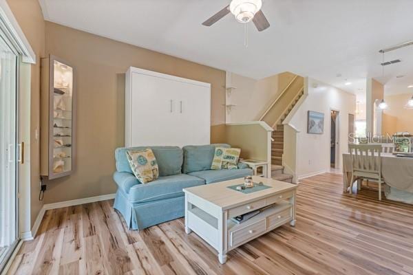 11162 Kapok Grand Cir, Madeira Beach, FL 33708 - living room with stairs, light wood-type flooring, and a ceiling fan