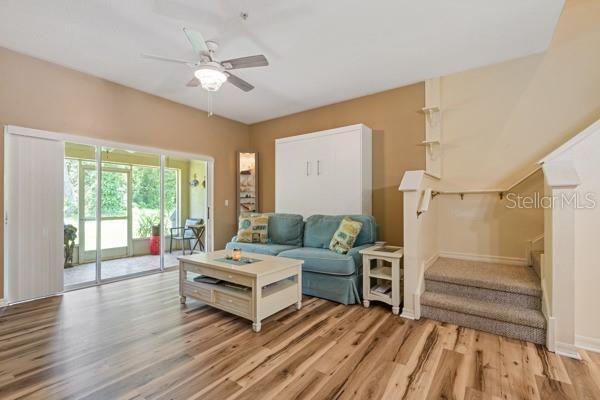11162 Kapok Grand Cir, Madeira Beach, FL 33708 - living room featuring light wood-style flooring, ceiling fan, and stairway