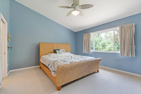 11162 Kapok Grand Cir, Madeira Beach, FL 33708 - carpeted bedroom featuring vaulted ceiling and a ceiling fan