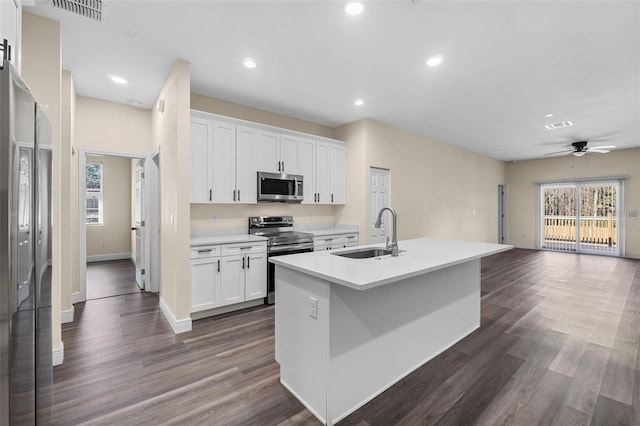 kitchen featuring visible vents, a sink, white cabinetry, open floor plan, and appliances with stainless steel finishes