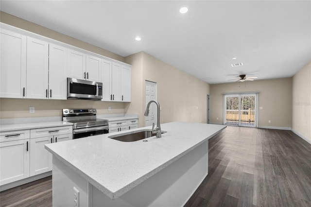 kitchen with a sink, stainless steel appliances, dark wood-type flooring, a center island with sink, and open floor plan