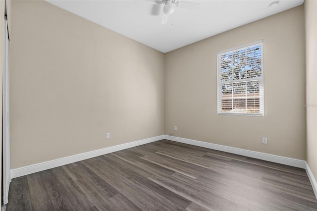spare room featuring baseboards, a ceiling fan, and dark wood finished floors