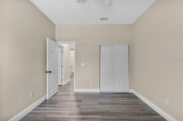 unfurnished bedroom with a closet, visible vents, baseboards, and dark wood-type flooring
