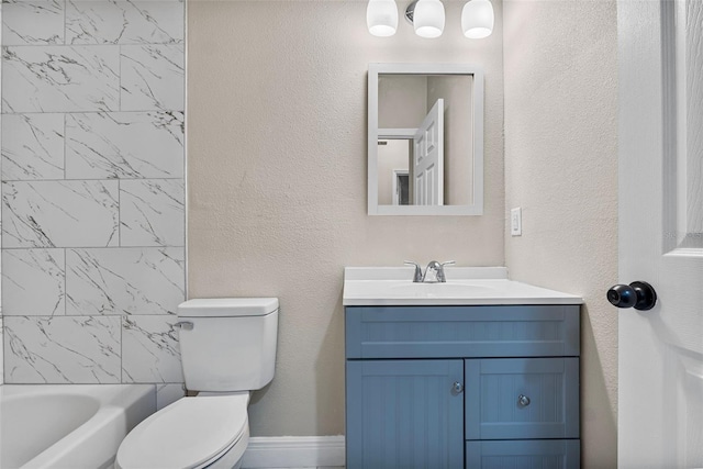 bathroom with vanity, toilet, a textured wall, and bathing tub / shower combination