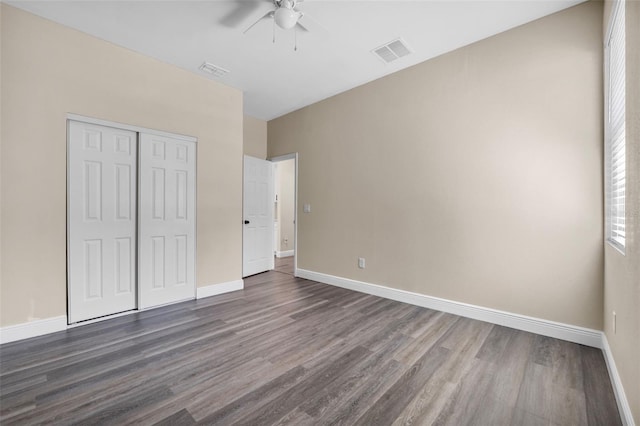 unfurnished bedroom with a closet, dark wood finished floors, and visible vents