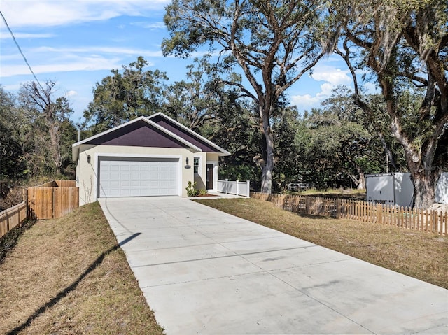 view of front facade with a front lawn, stucco siding, driveway, and fence