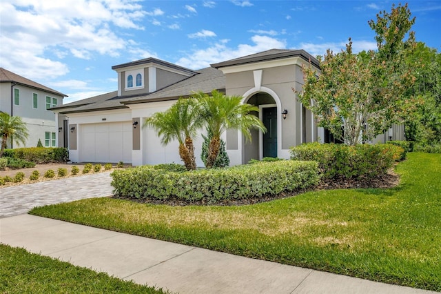 view of front of property featuring stucco siding, a front yard, decorative driveway, and a garage