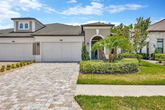 view of front of property featuring an attached garage, stucco siding, and decorative driveway